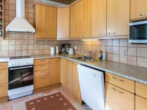 a kitchen with wooden cabinets and a white appliance at Holiday Home Ylläskankare by Interhome in Äkäslompolo