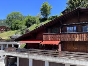 un edificio de madera con toldos rojos. en Apartment Chez-Nous by Interhome, en Gstaad