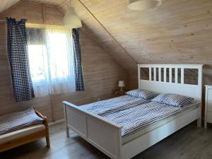 a bedroom with a white bed and wooden walls at Domki Balos in Karwia