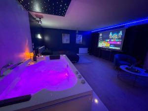 a room with a large pink bath tub with a tv at Spa sous les étoiles - Cinéma - Netflix - Parking - Gare in Amiens