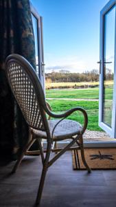 a chair sitting in front of a window at Loch Lomond Waterfront Luxury Lodges in Balmaha