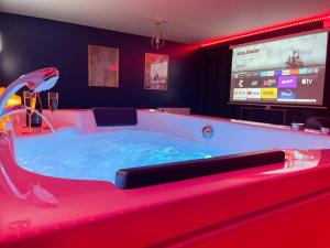 a hot tub in a room with a tv at Spa sous les étoiles - Cinéma - Netflix - Parking - Gare in Amiens