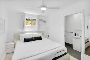- une chambre blanche avec un grand lit blanc et un lavabo dans l'établissement Private Outdoor Spa, Fire Pit, Cinema Room - THE COTTAGE COOLUM BEACH, à Coolum Beach 21 autres photos