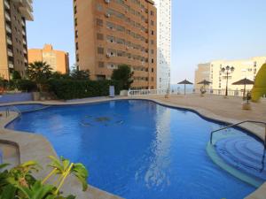 une grande piscine bleue avec des bâtiments en arrière-plan dans l'établissement Apartment Trinisol II Playa by Interhome, à Benidorm