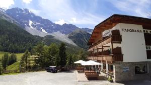 un hôtel avec des tables et des chaises en face d'une montagne dans l'établissement Pension Panorama, à Sulden