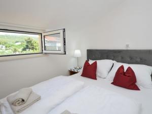 een slaapkamer met een wit bed met rode kussens en een raam bij Apartment Friedrich-7 by Interhome in Tribunj