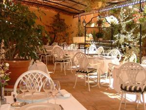 restauracja z białymi stołami, krzesłami i roślinami w obiekcie Hotel Moderne Et Pigeon w mieście Limoux