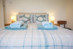 a bed with blue blankets and pillows on it at Valley Breeze in Bude