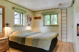a bedroom with a bed and two windows at Cottage 'Onder de boompjes' in Oostwoud
