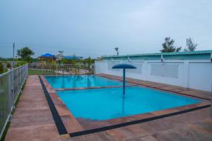 basen z parasolem w środku w obiekcie Hotel Surbhi w mieście Mundra