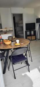 ein Holztisch und Stühle mit einer Schüssel Essen drauf in der Unterkunft La Cigale de Mer à 100 m de la Plage et du Centre Ville du Grau du Roi in Le Grau-du-Roi