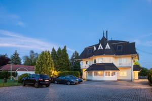a large house with two cars parked in a parking lot at Admiral Family Resort in Keszthely
