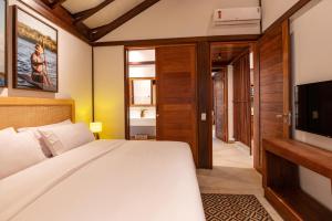 a bedroom with a large bed and a television at Colibri Beach Villas in Ilha de Boipeba
