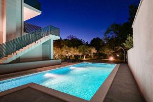 a swimming pool in the backyard of a house at night at Apartments Lacrima near the sea in Šilo