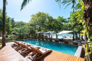 een zwembad in een resort met ligstoelen en de oceaan bij Colibri Beach Villas in Ilha de Boipeba