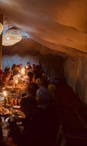 un groupe de personnes assises à une table dans une tente dans l'établissement Travel Oasis Merzouga Camp, à Merzouga
