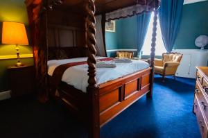 1 dormitorio con cama con dosel y silla en The George Hotel, Dereham en East Dereham