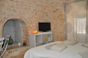 a bedroom with two beds and a tv in a stone wall at Il trullo di Mattia in Noci