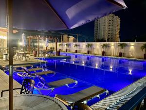 a swimming pool with blue lights in a city at night at Dona Olivia Residencial in Vitória da Conquista