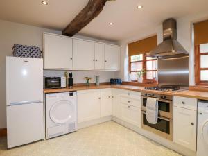 una cocina con armarios blancos y electrodomésticos de acero inoxidable en 13 The Island, en Totmonslow