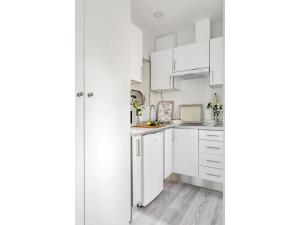 a white kitchen with white cabinets and a hardwood floor at Cozy studio (14m2) in Arturo Soria area D3 in Madrid