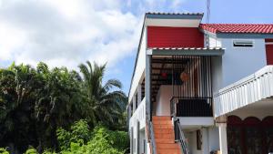 a building with a red door and a balcony at Bangtao Guest House in Bang Tao Beach
