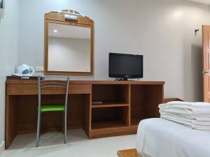 1 dormitorio con escritorio, TV y espejo en ก้านกล้วยแมนชั่น Gankluy Mansion en Phuket