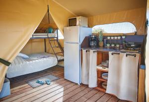 a kitchen and a refrigerator in a small tent at Camping des Papillons in Lalizolle