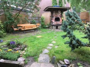 a garden with a wooden bench and a pizza oven at Vila Junda in Neringa