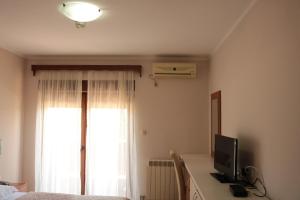 ein Schlafzimmer mit einem TV auf einem Schreibtisch mit einem Fenster in der Unterkunft Hotel Perjanik in Danilovgrad