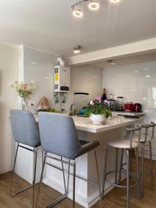 a kitchen with three bar stools and a counter at Los Mañios in Coihaique
