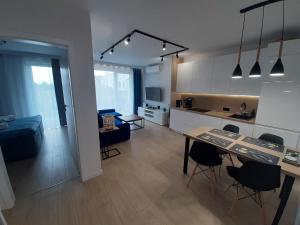 kuchnia i salon ze stołem i krzesłami w obiekcie Apartamenty Marzeń w Grzybowie
