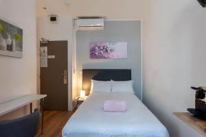 a bedroom with a bed with a pink pillow on it at Hotel l'Hotera in Cannes