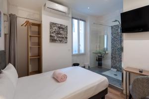 a bedroom with a bed and a tv and a bathroom at Hotel l'Hotera in Cannes