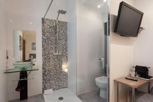a bathroom with a toilet and a tv on a wall at Hotel l'Hotera in Cannes
