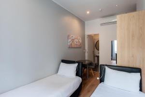 a bedroom with two beds and a table in it at Hotel l'Hotera in Cannes