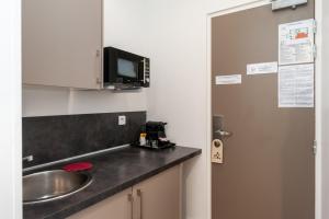 a kitchen with a sink and a microwave at Hotel l'Hotera in Cannes
