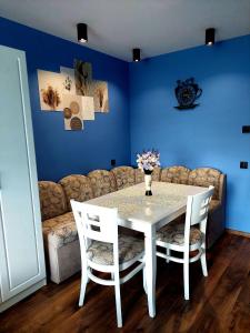 una mesa y sillas blancas en una habitación con una pared azul en Zara Apartment, en Gorna Oryakhovitsa