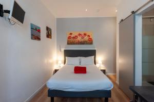 a bedroom with a bed with a red pillow on it at Hotel l'Hotera in Cannes