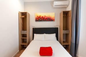 a bedroom with a bed with a red pillow on it at Hotel l'Hotera in Cannes