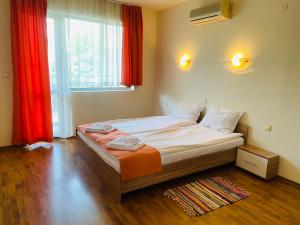 a bedroom with a large bed with red curtains at Black Sea View Apartments in Ravda