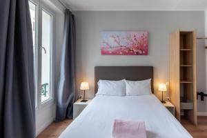 a bedroom with a white bed and a window at Hotel l'Hotera in Cannes