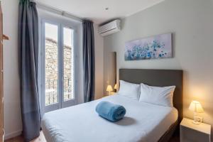 a bedroom with a bed with a blue pillow on it at Hotel l'Hotera in Cannes