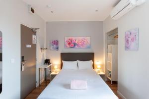 a bedroom with a bed and two paintings on the wall at Hotel l'Hotera in Cannes