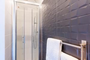 a bathroom with a shower and a white towel at Hotel l'Hotera in Cannes