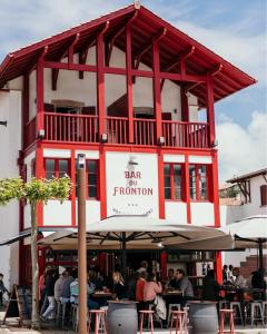 un edificio rojo y blanco con gente sentada en las mesas en Hotel du Fronton, en Bidart