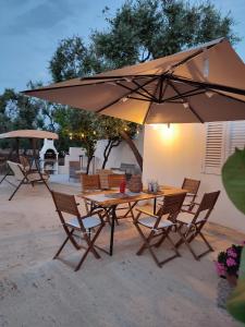 een houten tafel en stoelen met een parasol bij Casedda Ostunese in Ostuni