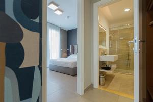 a bedroom with a bed and a bathroom with a shower at Mosella Suite Hotel in Sottomarina