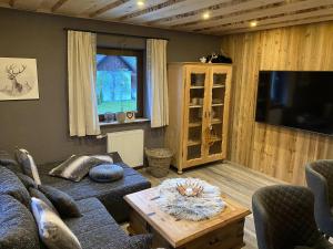 a living room with a couch and a tv at Chalet am Weißenbach in Hinterstoder