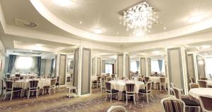 a dining room with tables and chairs and a chandelier at Hotel Parc Sibiu in Sibiu